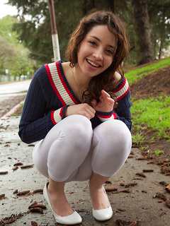 Curly hair teen cutie plays outdoors in a sweater and sheer tights